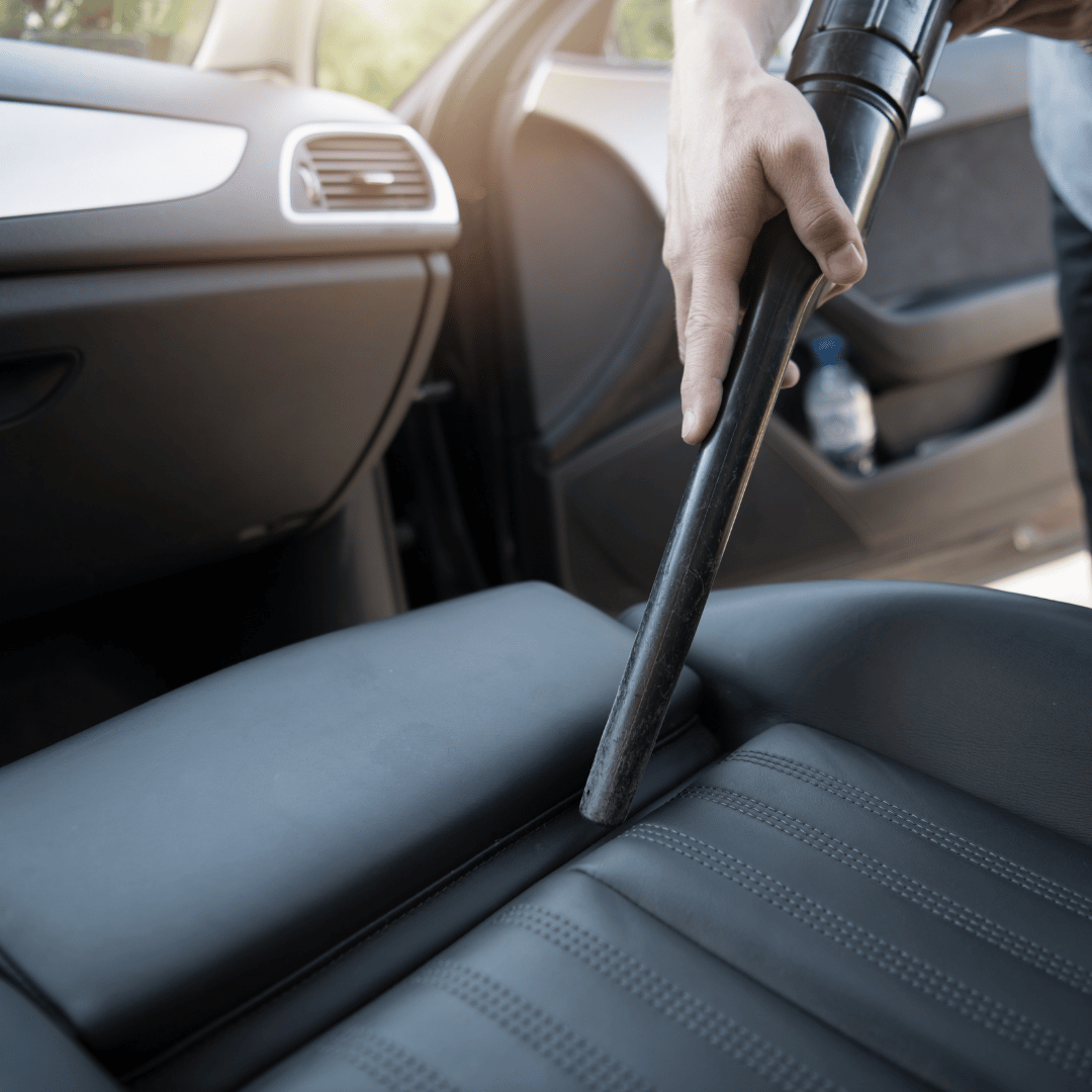 Hand vacuuming a car's rear seat through an open door